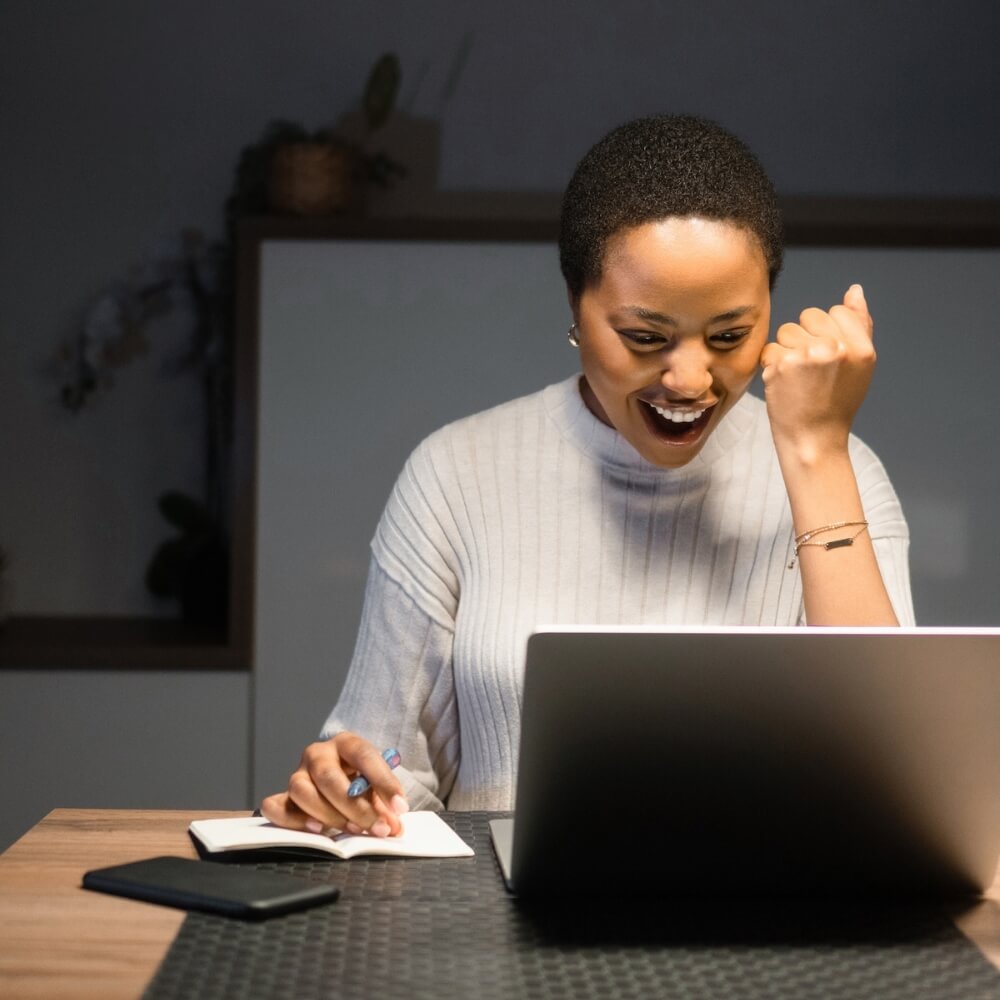 Woman cheering at her laptop